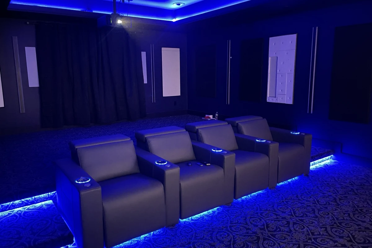 Private home theater with blue architectural lighting and theater seating